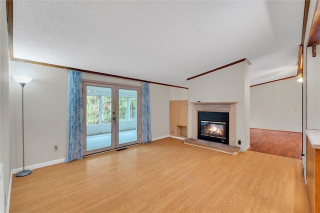 unfurnished living room with visible vents, a glass covered fireplace, light wood-style flooring, ornamental molding, and french doors