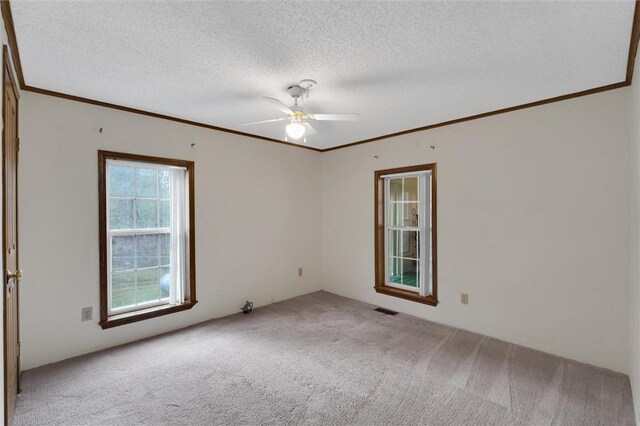 spare room featuring carpet, crown molding, visible vents, a ceiling fan, and a textured ceiling