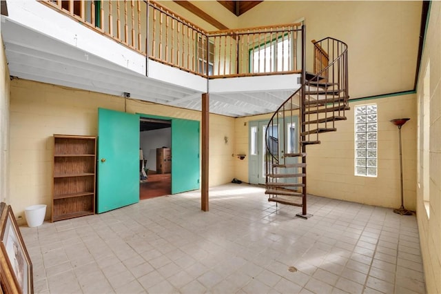 interior space with concrete block wall, a high ceiling, and stairs