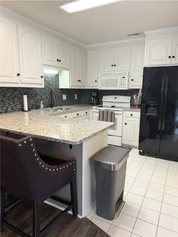 kitchen featuring white appliances, white cabinets, decorative backsplash, a breakfast bar area, and kitchen peninsula