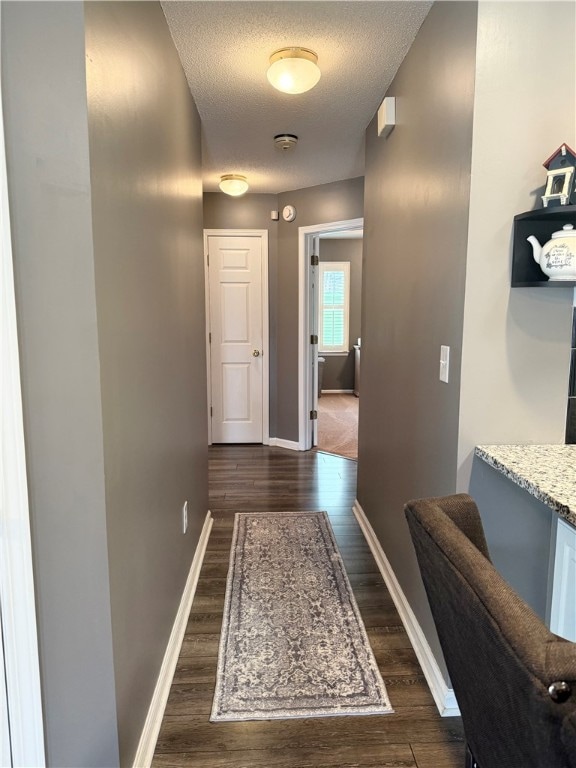 hallway featuring dark wood-type flooring and a textured ceiling