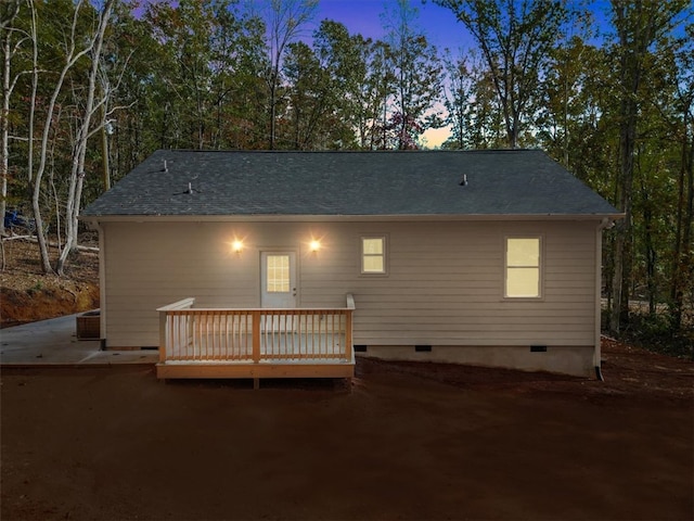 back house at dusk with central air condition unit, a wooden deck, and a patio area