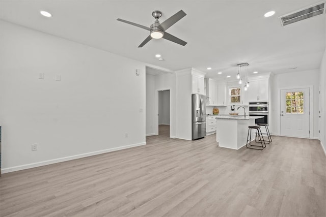 living room featuring light hardwood / wood-style floors, ceiling fan, and sink