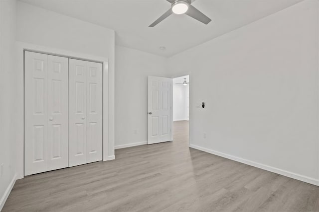 unfurnished bedroom with light wood-type flooring, ceiling fan, and a closet