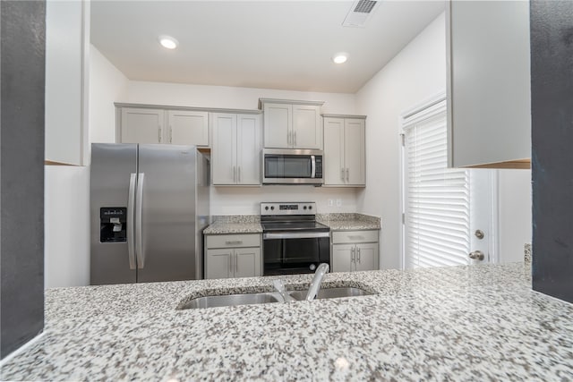 kitchen with light stone countertops, sink, appliances with stainless steel finishes, and gray cabinets