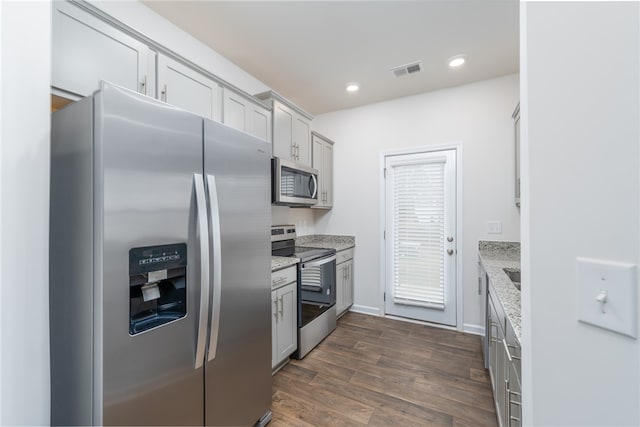 kitchen with stainless steel appliances, light stone countertops, sink, and dark hardwood / wood-style flooring