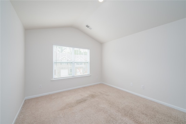 unfurnished room featuring light colored carpet and vaulted ceiling