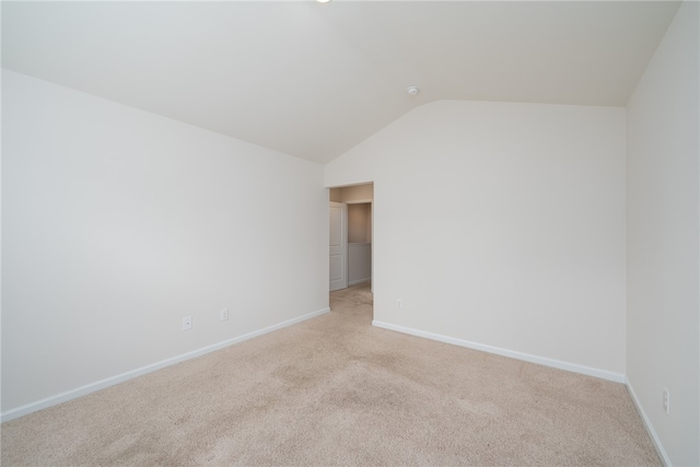 unfurnished room featuring vaulted ceiling and light colored carpet