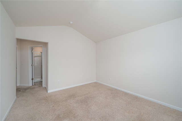 unfurnished room featuring light colored carpet and vaulted ceiling