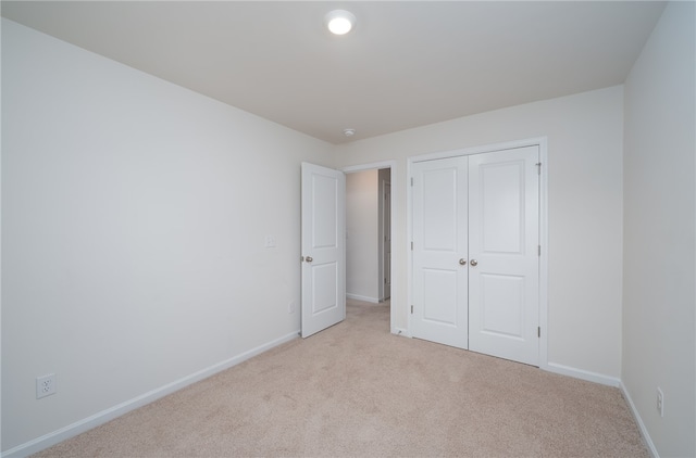 unfurnished bedroom with light carpet and a closet