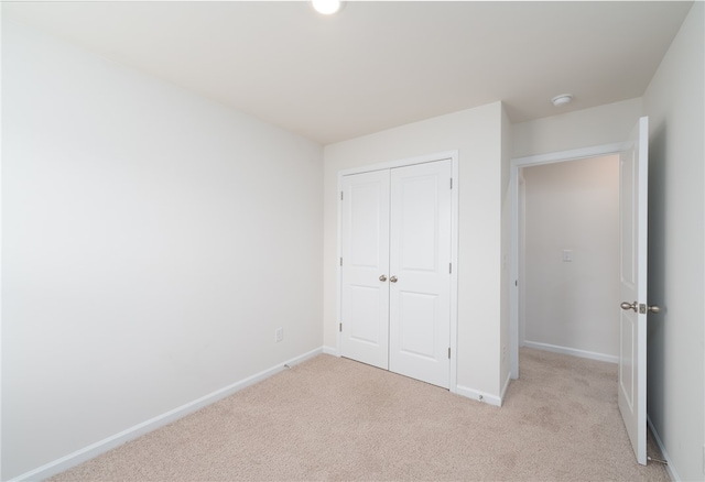 unfurnished bedroom featuring light colored carpet and a closet