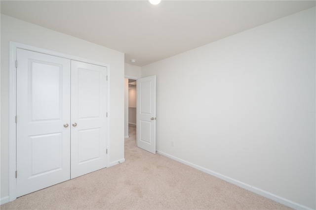 unfurnished bedroom featuring a closet and light carpet