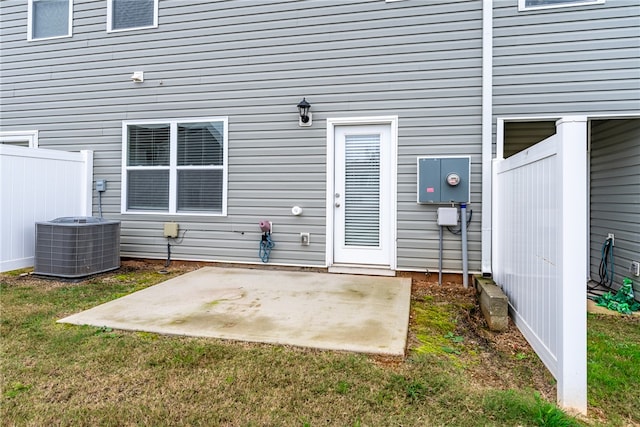 view of exterior entry with central AC, a yard, and a patio area