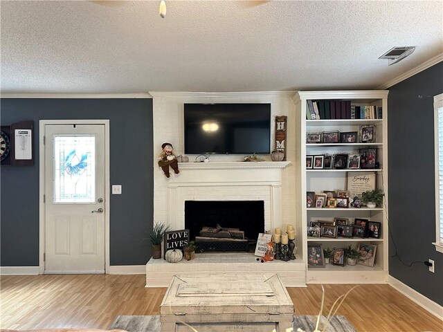 living room with crown molding, a fireplace, light hardwood / wood-style floors, and a textured ceiling