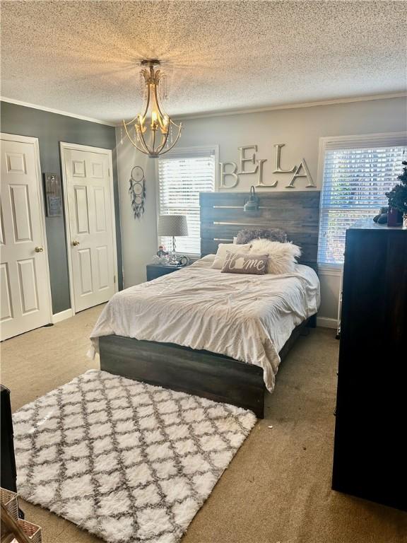 carpeted bedroom featuring multiple windows, a chandelier, and a textured ceiling