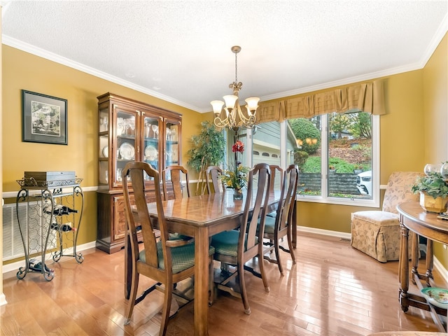 dining area with light wood-type flooring, a notable chandelier, a textured ceiling, and crown molding