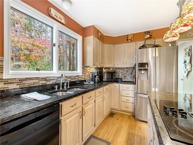 kitchen with stainless steel appliances, light hardwood / wood-style floors, sink, dark stone counters, and pendant lighting