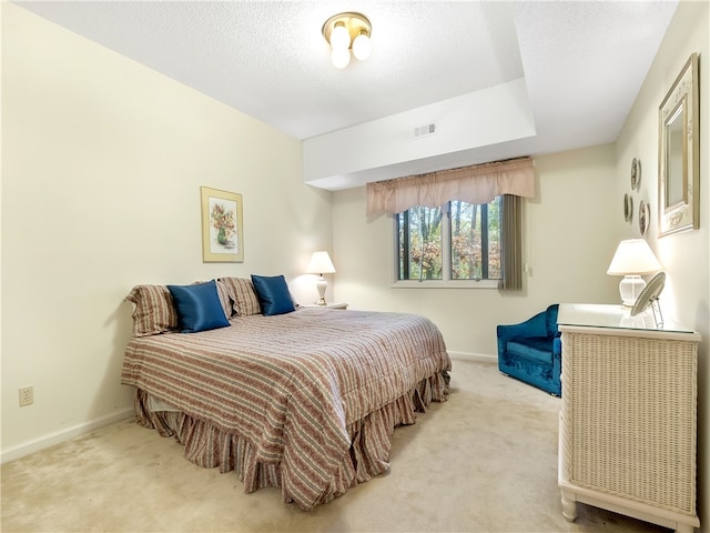 bedroom featuring light colored carpet and a textured ceiling