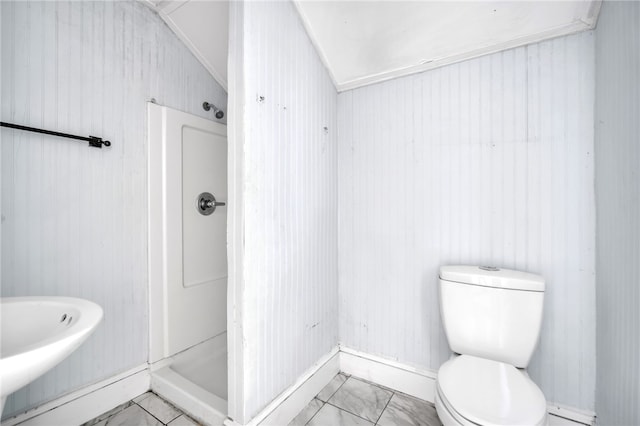 bathroom with toilet, a shower, wooden walls, and vaulted ceiling