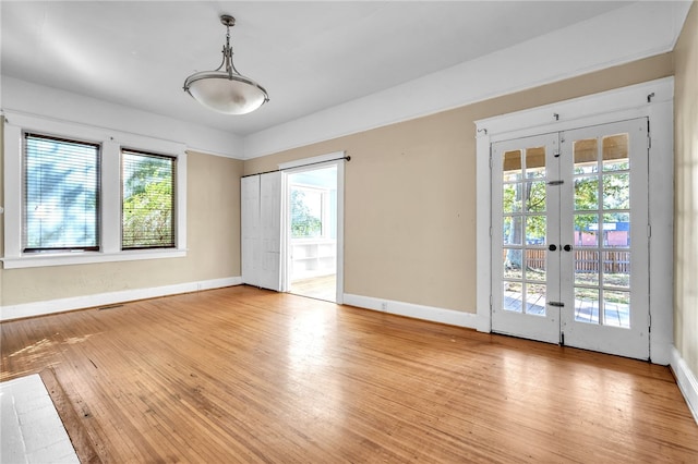 unfurnished room featuring plenty of natural light, light wood-type flooring, and french doors