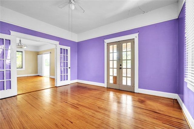 empty room with ceiling fan, light wood-type flooring, and french doors