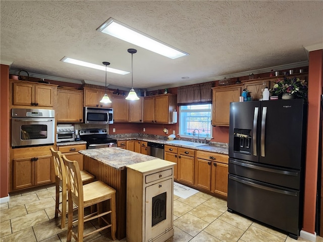 kitchen with sink, appliances with stainless steel finishes, a breakfast bar area, hanging light fixtures, and a kitchen island