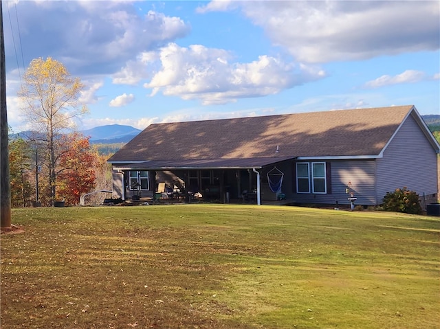 rear view of house with a lawn and a mountain view