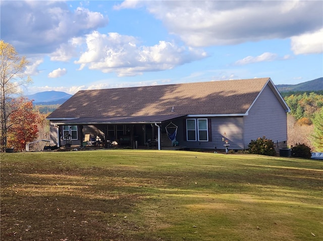 rear view of property featuring central AC, a yard, and a mountain view