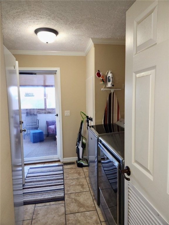 laundry room with a textured ceiling, washer and clothes dryer, crown molding, and light tile patterned floors