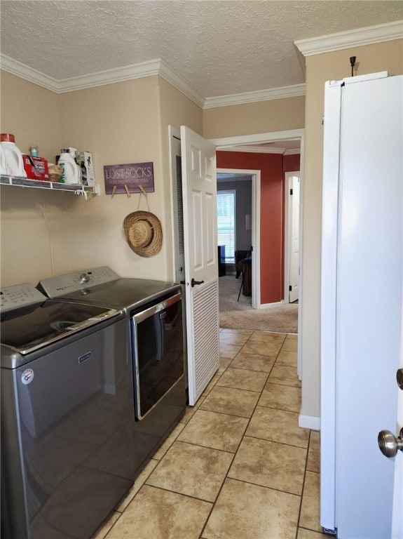 washroom featuring ornamental molding, a textured ceiling, light tile patterned floors, and independent washer and dryer