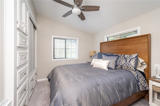 bedroom with a closet, vaulted ceiling, light colored carpet, and ceiling fan