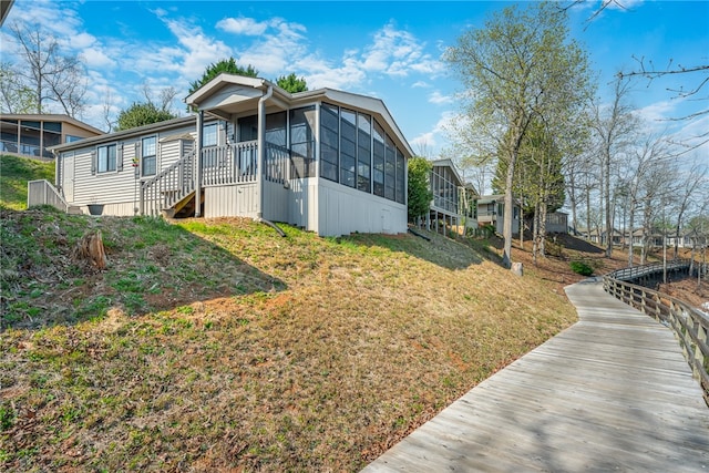 view of home's exterior featuring a sunroom and a yard