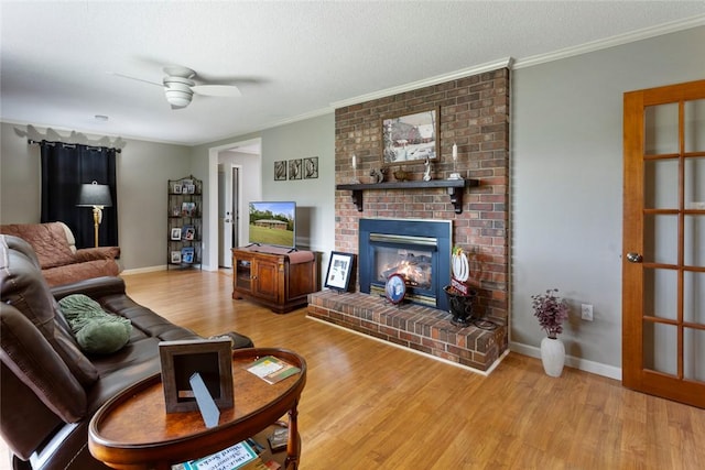 living room with a brick fireplace, hardwood / wood-style flooring, ceiling fan, ornamental molding, and a textured ceiling