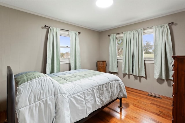 bedroom featuring hardwood / wood-style floors, multiple windows, and ornamental molding