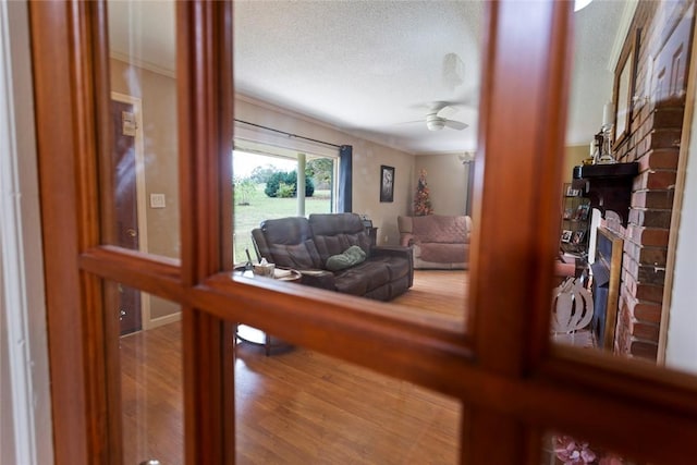 living room with hardwood / wood-style flooring, ceiling fan, a fireplace, and a textured ceiling