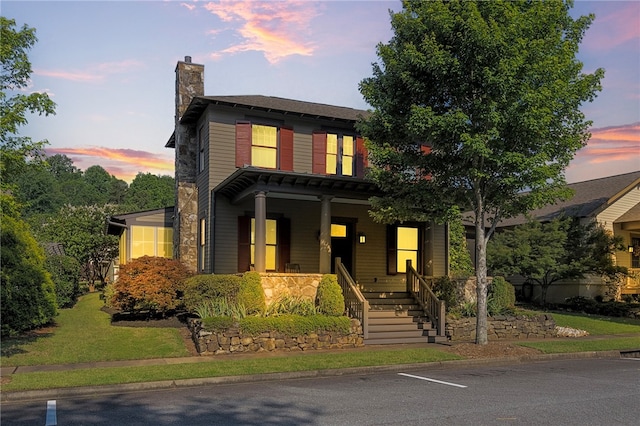 view of front of home with covered porch and a lawn