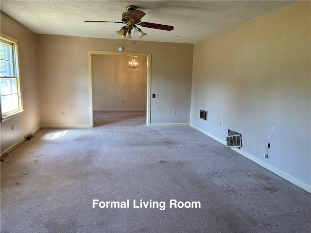 spare room featuring carpet flooring, ceiling fan with notable chandelier, and a textured ceiling