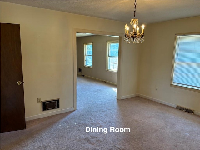 carpeted empty room featuring an inviting chandelier