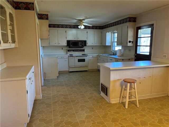 kitchen with a kitchen bar, kitchen peninsula, range with two ovens, and white cabinets