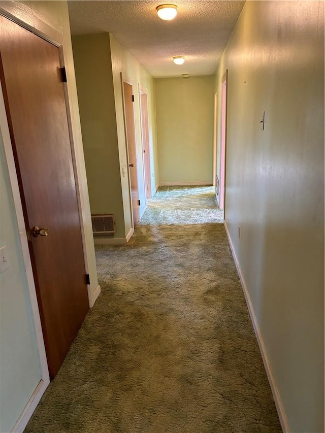 hallway featuring carpet flooring and a textured ceiling