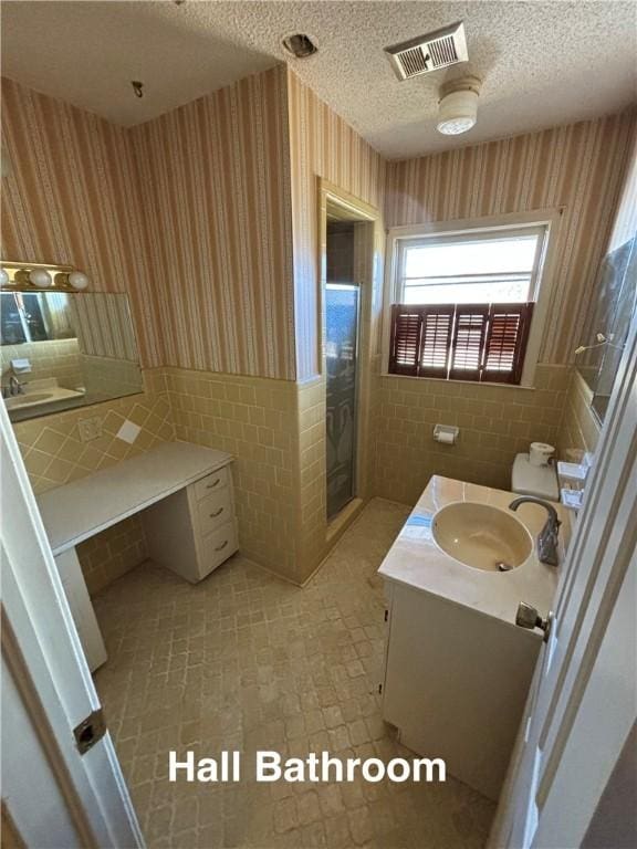 bathroom featuring tile walls, vanity, an enclosed shower, a textured ceiling, and toilet