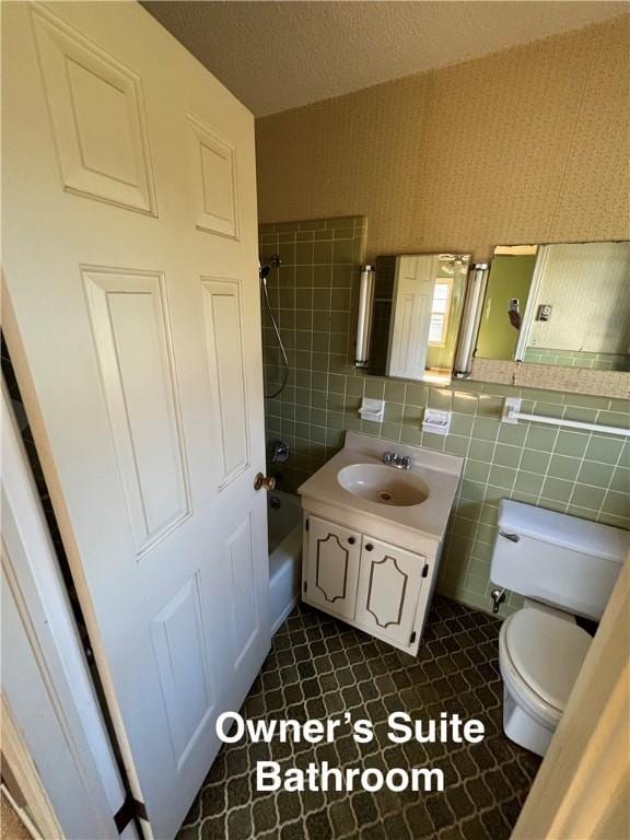 full bathroom featuring bathing tub / shower combination, tile walls, vanity, and toilet