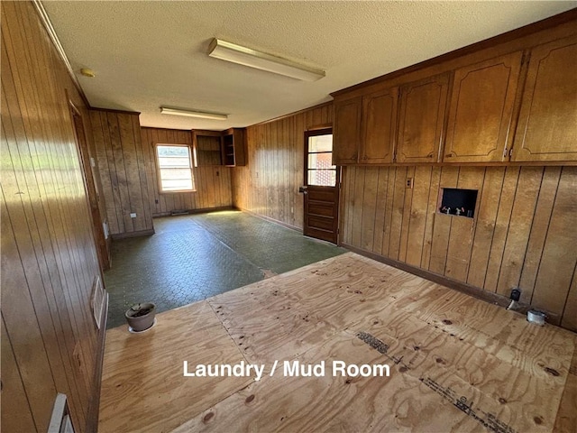 unfurnished room with a textured ceiling and wood walls