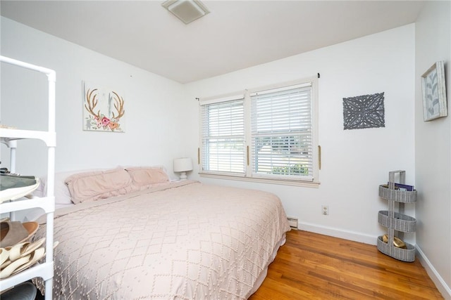 bedroom featuring hardwood / wood-style floors and baseboard heating