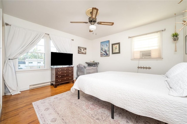 bedroom featuring a baseboard heating unit, wood-type flooring, and ceiling fan