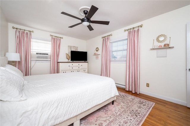 bedroom featuring a baseboard radiator, hardwood / wood-style floors, ceiling fan, and cooling unit