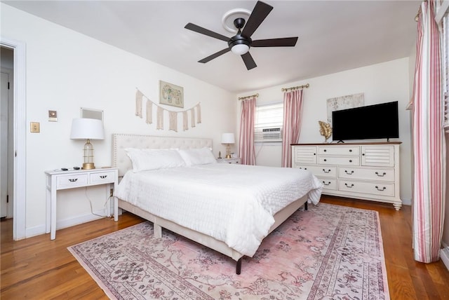 bedroom featuring cooling unit, hardwood / wood-style floors, and ceiling fan