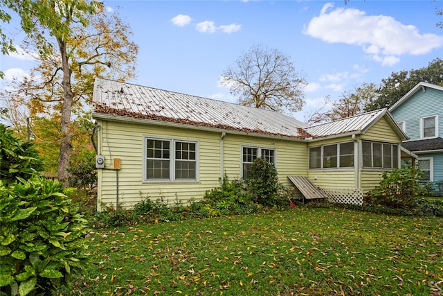 back of property with a sunroom and a yard