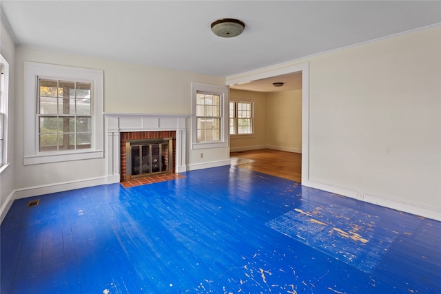 unfurnished living room featuring hardwood / wood-style floors, a wealth of natural light, and a brick fireplace