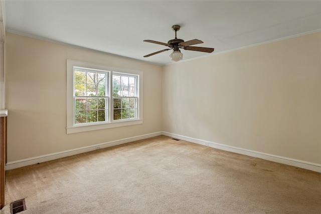 spare room with ceiling fan, light carpet, and crown molding